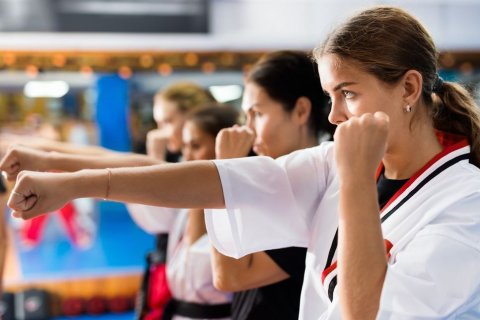 Foto: BearFotos / shutterstock Wir schauen seitlich auf eine Reihe Frauen, die jeweils ihren rechten Arm mit geballter Faust nach vorne ausgestreckt haben, während der linke nach oben angewinkelt ist. Auch hier bildet die Hand jeweils eine Faust. Sie schauen konzentriert nach vorne.