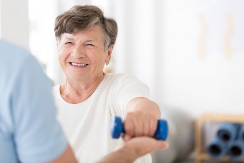 Foto: Ground Picture / shutterstock Eine Seniorin macht unterstützte Übungen mit einer kleinen blauen Hantel.