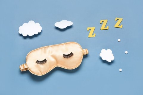 Diese Collage zeigt vor hellblauem Hintergrund eine goldene Schlafmaske mit aufgeklebten schwarzen Wimpern, wei&szlig;e W&ouml;lkchen und dreimal den Buchstaben Z sowie drei wei&szlig;e Punkte. 